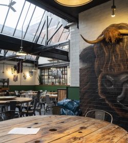 Inside of restaurant showing table layouts. Giant cow image on wall.